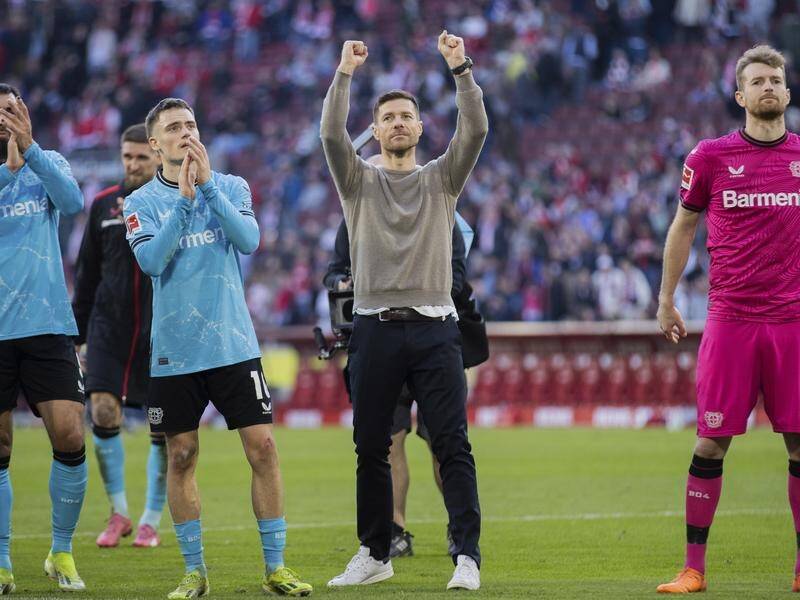 Leverkusen coach Xabi Alonso raises his arms aloft after the Bundesliga leaders' 2-0 win at Cologne. (AP PHOTO)